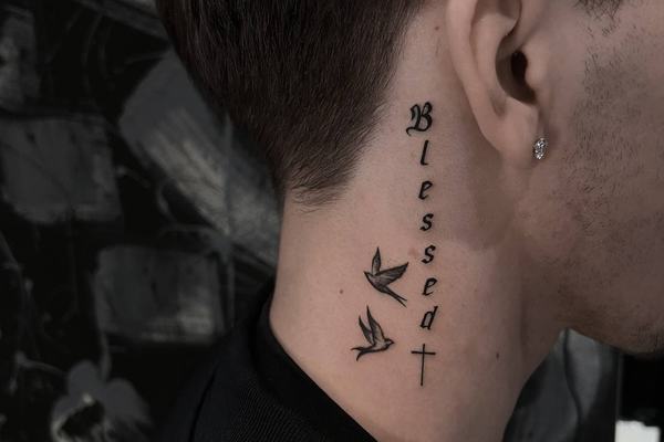 Widoczny tatuaż na szyi: Blessed, krzyż i jaskółki