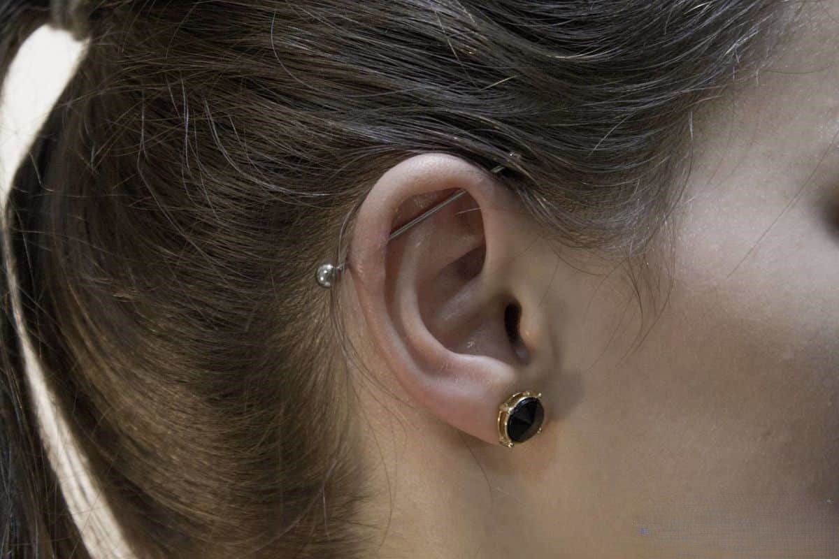 Delikatny srebrny piercing industrial na uchu.