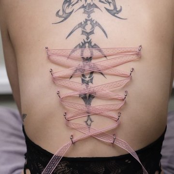 Piercing gorsetowy na plecach z różową wstążką
