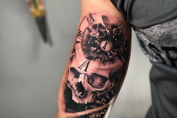 Tatuaż męski na bicepsie – czaszka i zegar