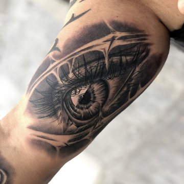 Tatuaż oko w realistycznym stylu na bicepsie mężczyzny