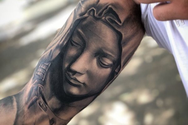 Tatuaż męski na bicepsie  twarz kobiety w realistycznym stylu