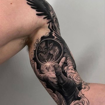 Tatuaż dłoń z kulą ziemską na bicepsie mężczyzny