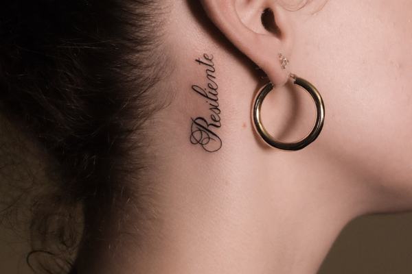 Mały tatuaż tekstowy za uchem 