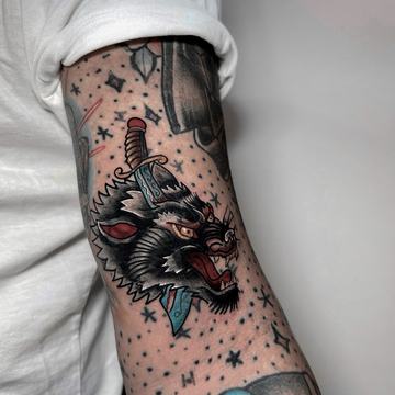 Ramię: kompozycja tatuaży – wilk z nożem, różna skala