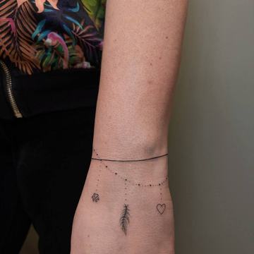 Delikatny tatuaż na nadgarstku: piórko i serce