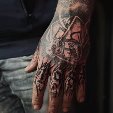Tatuaż na dłoni: kości i litery, gęsty czarny styl