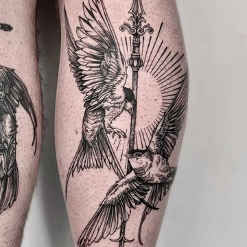 Tatuaż męski na łydce z motywem ptaków i włóczni