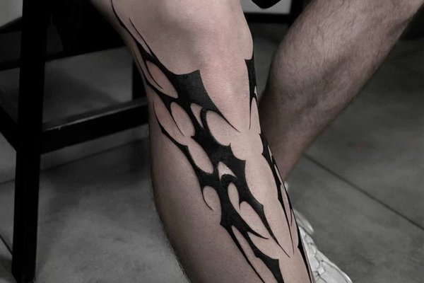 Czarny tribal tatuaż męski na nodze