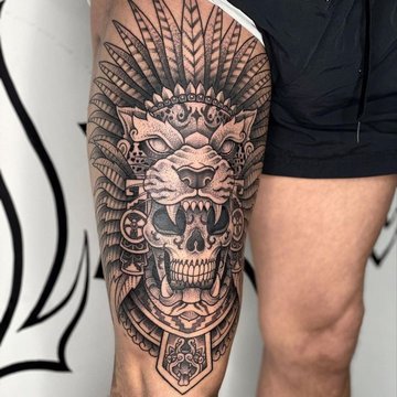 Tatuaż męski na udzie z motywem lwa i czaszki