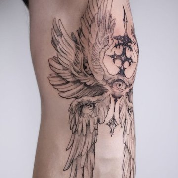 Tatuaż męski na nodze z motywem skrzydeł i oka