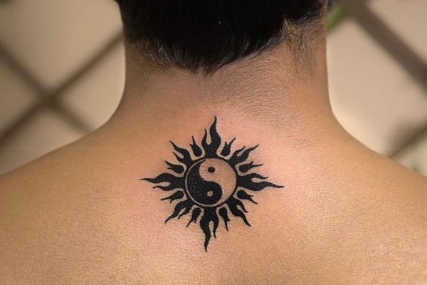 Tatuaż na karku z symbolem yin-yang otoczonym płomieniami