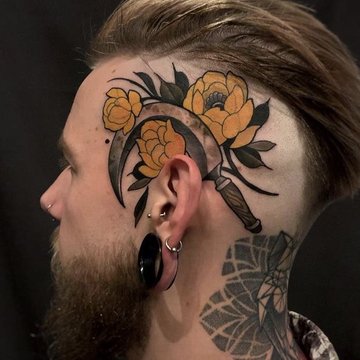 Tatuaż za uchem męski – sierp z żółtymi kwiatami