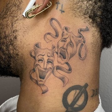 Tatuaż za uchem męski – maski teatralne komedii i tragedii