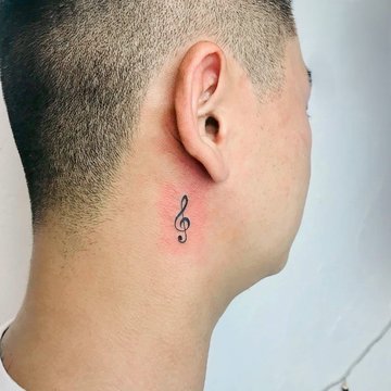 Tatuaż za uchem męski – mały klucz wiolinowy