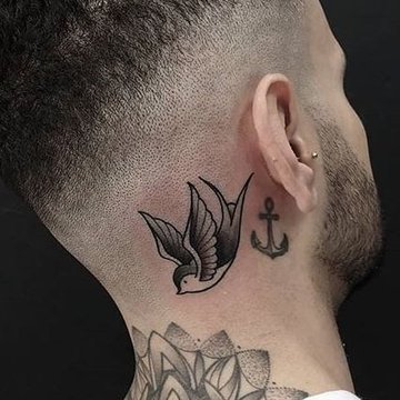 Tatuaż za uchem męski – jaskółka i kotwica