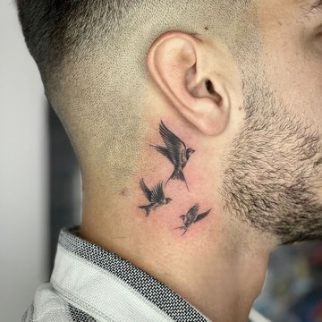 Tatuaż za uchem męski – trzy lecące ptaki