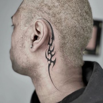 Tatuaż za uchem męski – czarny tribal w stylu ognia