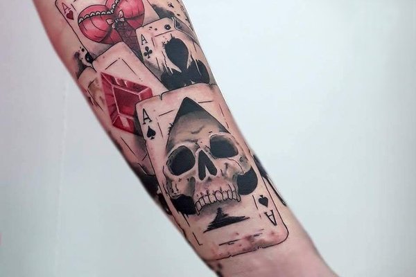Tatuaż na nadgarstku męski z kartami i czaszką w stylu realistycznym