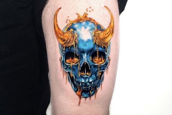 Tatuaż na udzie męski – kolorowa czaszka z rogami w ogniu
