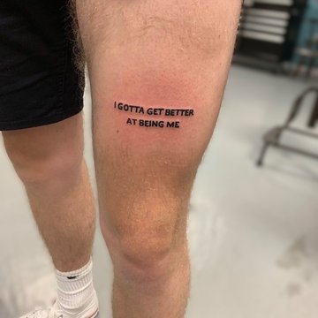 Tatuaż na udzie męski - minimalistyczny napis