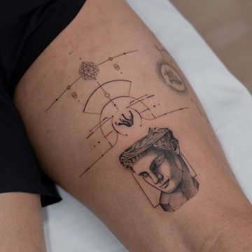 Tatuaż na udzie męski – minimalistyczny motyw z greckim popiersiem i geometrycznymi liniami