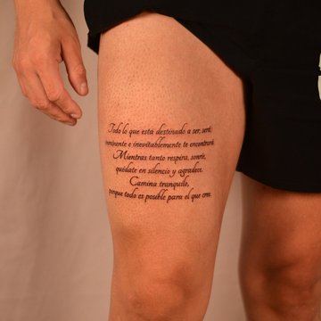 Tatuaż na udzie męski – napis po hiszpańsku o spokoju i wdzięczności