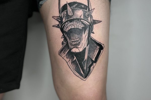 Tatuaż na udzie męski – demoniczna postać z kolcami i szerokim uśmiechem