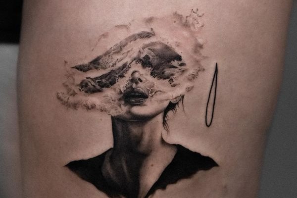 Tatuaż na udzie męski – surrealistyczny portret kobiety z efektem dymu