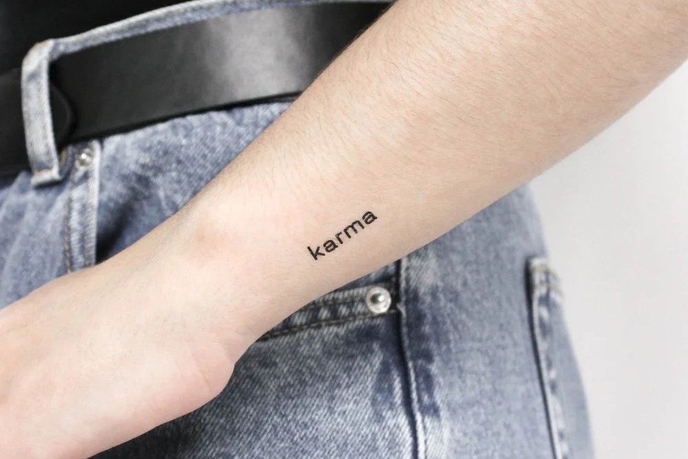 tatuaż z napisem karma na przedramieniu