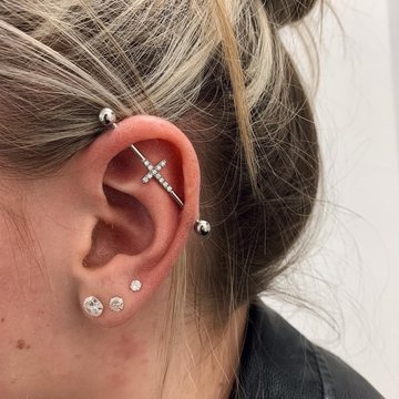 Srebrny piercing industrial z ozdobnym krzyżykiem w chrząstce ucha