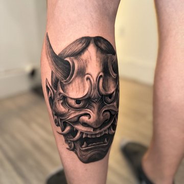 Tatuaż męski maska demona na łydce