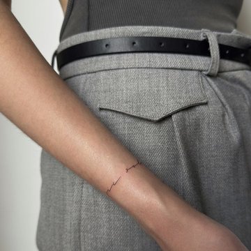 Małe tatuaże damskie napis na przedramieniu kobiety