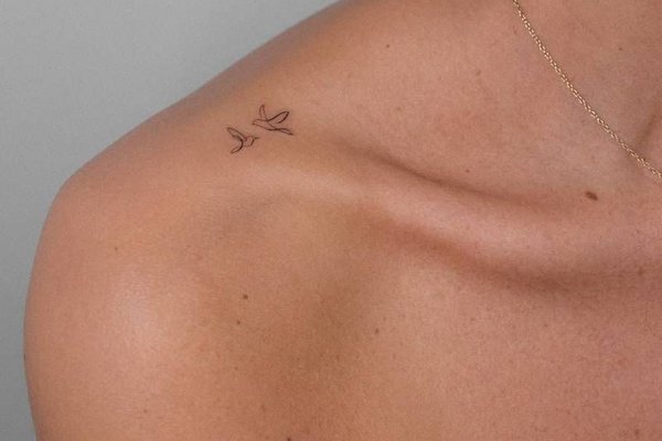 Małe tatuaże dwóch ptaków na ramieniu kobiety