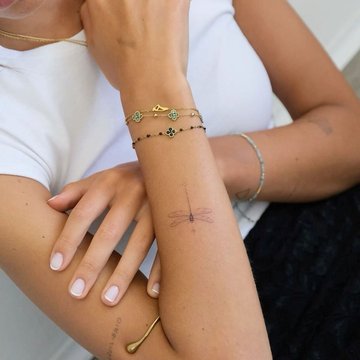 Małe tatuaże ważki na przedramieniu kobiety w stylu minimalistycznym