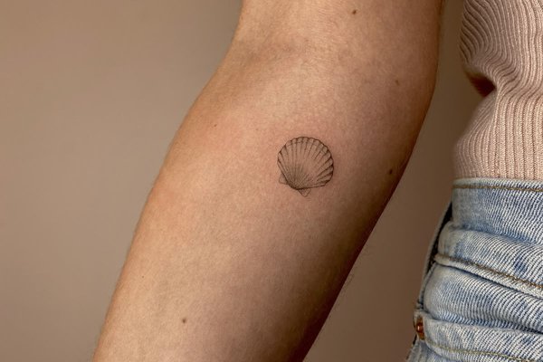 Małe tatuaże muszli na przedramieniu kobiety