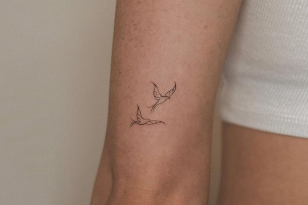 Małe tatuaże gałązki na przedramieniu kobiety w stylu linearnym