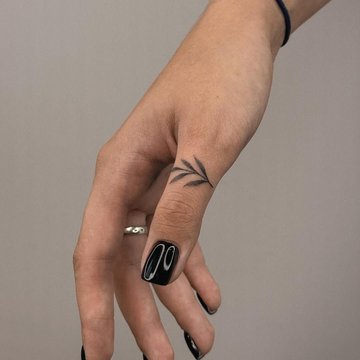 Małe tatuaże liścia na dłoni kobiety w stylu fine line