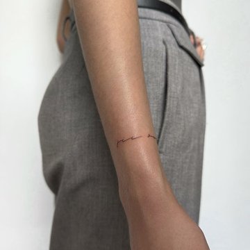 Małe tatuaże napisu na przedramieniu kobiety