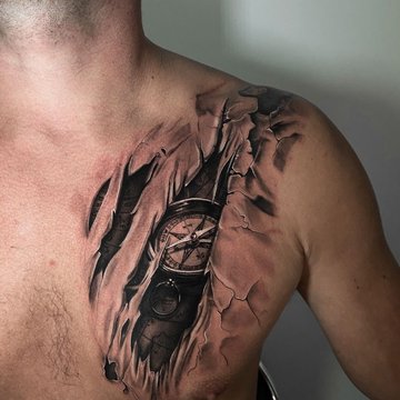 Tatuaż na klatce piersiowej męski – realistyczny kompas w efekcie rozdartej skóry