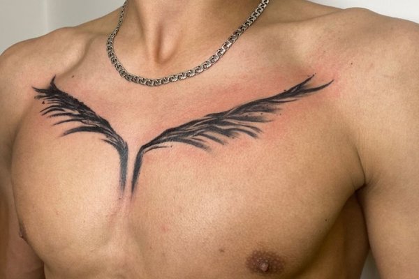 Tatuaż na klatce piersiowej męski – minimalistyczne skrzydła w czarnym tuszu