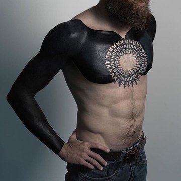 Tatuaż na klatce piersiowej męski – blackout z mandalą w centrum