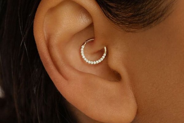 Zbliżenie na daith piercing z złotym kolczykiem
