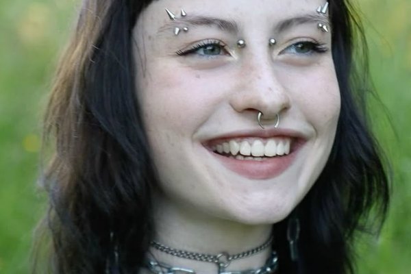 Uśmiechnięta osoba z bridge piercingiem i septum
