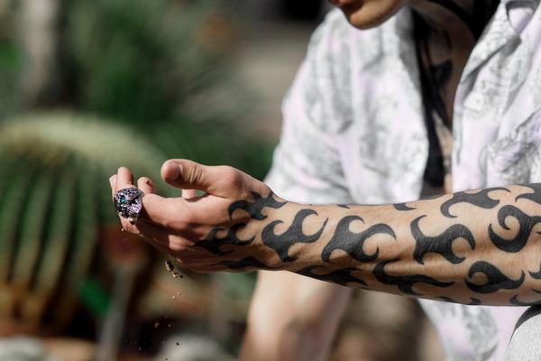 Czarne tatuaże na szyi i przedramieniu w słońcu