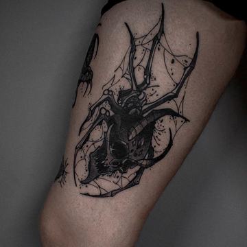 Tatuaż pająka z siecią na udzie — dużo czerni i detali