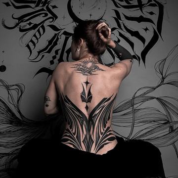 Kompozycja czarnych tatuaży różnej skali na plecach