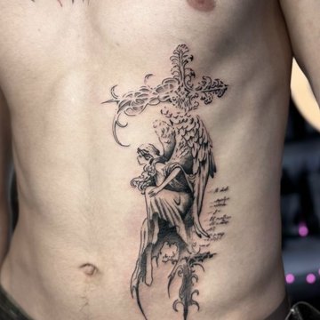 Tatuaż anioł z krzyżem na żebrach męski symbol wiary i duchowej ochrony